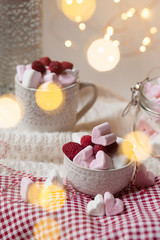 Special delicious breakfast on Saint Valentine day: pink heart shaped marshmallow and fresh raspberry nicely decorated with lights and vintage lamp. Festive mood, holiday inspiration