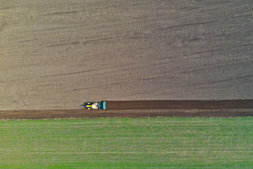 Aerial view on polish rural area with old tractor while plowing the soil on wheat field before sowing the seeds.