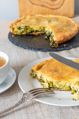 A piece of delicious vegan homemade pie with broccoli and cheese on a white plate closeup - vegetarian, healthy cuisine.