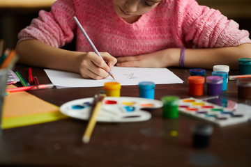 Cropped portrait of unrecognizable girl drawing picture with pencil in art class, copy space