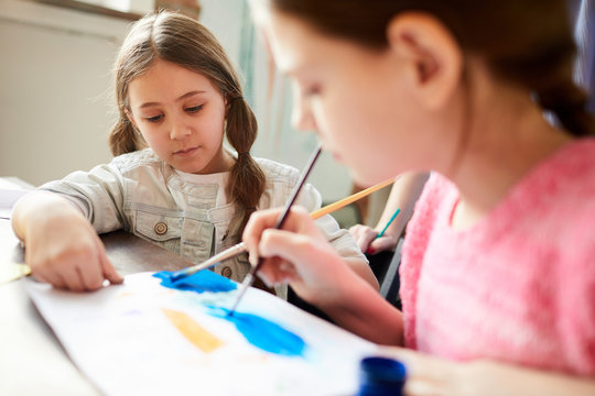 Closeup of two little girls painting picture together in art class or at home, copy space