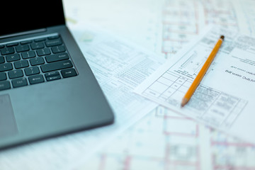 Pencil and computer laptop on architectural drawing paper for construction