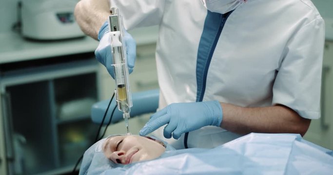 Portrait of a doctor man make a new procedure of vampirefacial or prp , new technology mature woman patient make a micro-needling procedure.