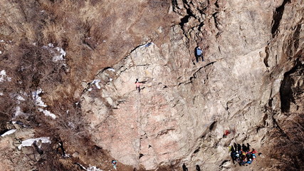 Climbers climb the rock. Drone footage. Side and top view. Rock lesson in the highlands. Gray rocks...