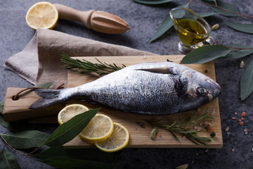 Mediterranean seafood concept. Raw dorado fish with olive oil, lemon, rosemary on stone table. Fresh organic sea bream or dorada fish. Top view dorado fish