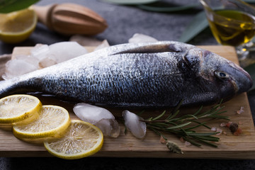 Mediterranean seafood concept. Raw dorado fish with olive oil, lemon, rosemary on stone table. Fresh organic sea bream or dorada fish. Top view dorado fish