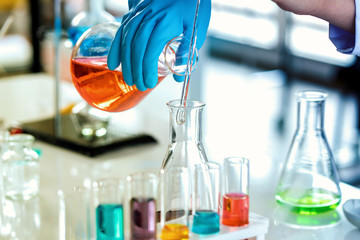 scientist with equipment and science experiments, laboratory glassware containing chemical liquid for research or analyzing a sample into test tube in laboratory