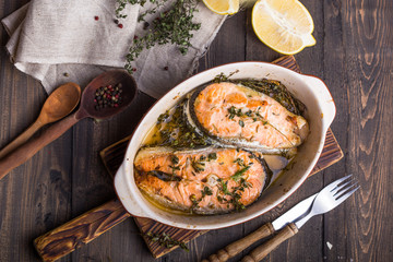 Grilled fish, grilled salmon steak with addition of lemon,  and spices on grill bowl, close-up.