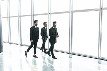 Fototapeta premium Businesspeople moving along the corridor with big panoramic windows