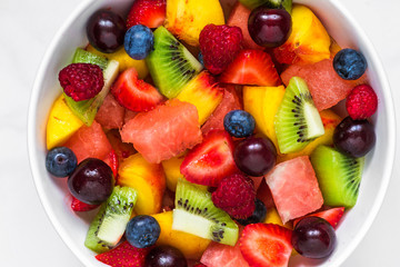 fruit salad with watermelon, strawberry, cherry, blueberry, kiwi, raspberry and peaches in a bowl. healthy vegan food