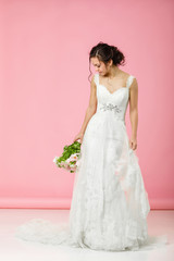 beautiful bride with wedding bouquet of pink tulips on pink background