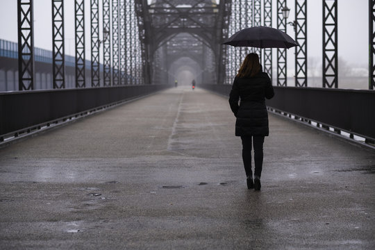 Girl walking on bridge on a rainy day