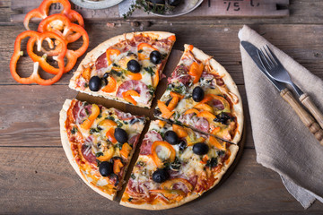 Pizza with tomatoes, mozzarella cheese, black olives and basil. Delicious italian pizza on wooden pizza board.