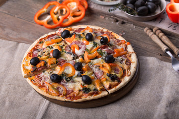 Pizza with tomatoes, mozzarella cheese, black olives and basil. Delicious italian pizza on wooden pizza board.