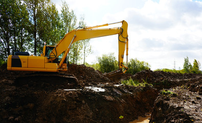 yellow excavator digs the ground
