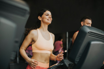Fototapeta na wymiar Young couple running on treadmills in modern gym