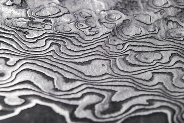 Background with pattern of damask steel. Close up. Macro shot of a damascus knife blade texture....