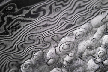Background with pattern of damask steel. Close up. Macro shot of a damascus knife blade texture. Damascus steel pattern. Metal and steel background. Damascus steel with original pattern.