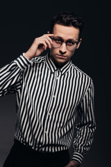 Handsome man with glasses, toung man in striped shirt, black background