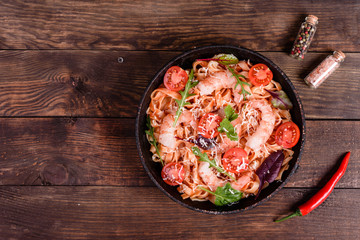 Tasty pasta with shrimp and tomato on a frying pan