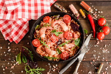 Tasty pasta with shrimp and tomato on a frying pan