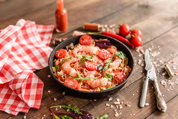 Tasty pasta with shrimp and tomato on a frying pan