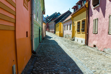 Obraz premium Kolorowe wąskie średniowieczne uliczki w jasny wiosenny dzień w Sighisoara, Rumunia.