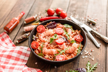 Tasty pasta with shrimp and tomato on a frying pan
