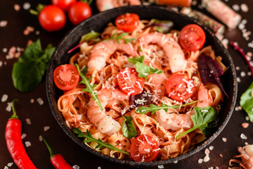 Tasty pasta with shrimp and tomato on a frying pan