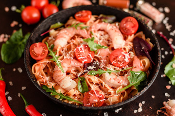 Tasty pasta with shrimp and tomato on a frying pan