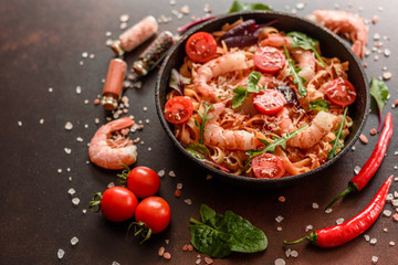 Tasty pasta with shrimp and tomato on a frying pan