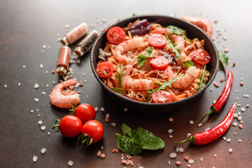 Tasty pasta with shrimp and tomato on a frying pan