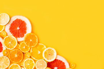 Juicy fresh bright summer yellow background with citrus fruits, flat lay. Sliced mixed citrus...