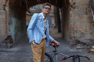 Stylish young man posing on the street on a retro bike.