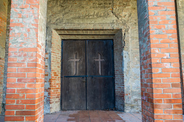 Medieval lutheran church entrance, brick pylons, hand carved cross on the door.