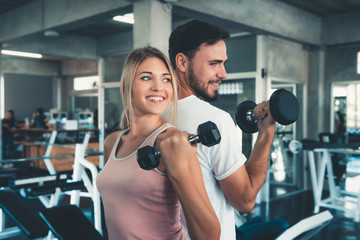 Fototapeta na wymiar Portrait of Couple Love in Fitness Training With Dumbbell Equipment., Young Couple Caucasian are Working Out and Training Together in Gym Club., Sport and Healthy Concept.