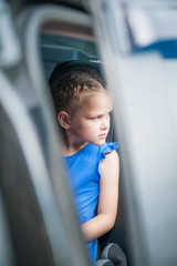 Cute girl is sitting in the car with the door open