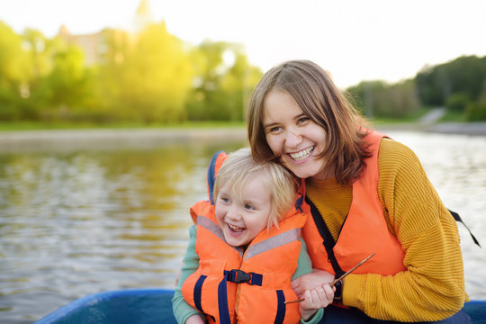 Young Mother And Little Son Boating On A River Or Pond At Sunny Summer Day. Quality Family Time Together On Nature.