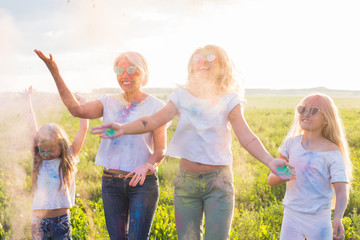 Fototapeta premium Friendship, Indian holidays and people concept - young women and children dancing on the summer field on festival of holi