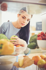 Smiling woman taking a fresh fruit out of the fridge, healthy food concept