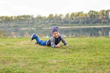Naklejka na ściany i meble Children and childhood concept - Smiling little boy laying on the grass