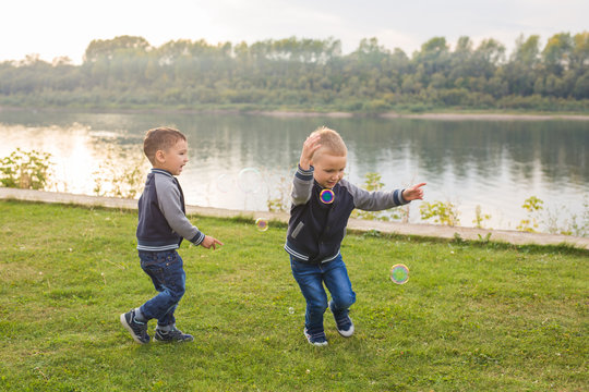 Children and childhood concept - Two brothers boys playing with colorful soap bubbles