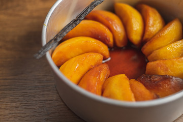 Cooked apple pieces with caramel arrange in a metal cake tin on wood table top.	