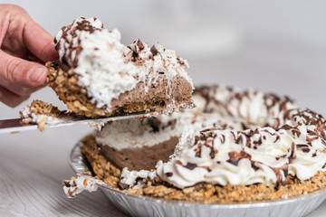 Closeup of hand taking a piece of delicious cream pie ready to server, Cream and chocolate topping