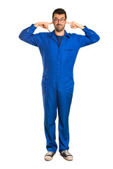A full-length shot of a Painter man covering both ears with hands on isolated white background
