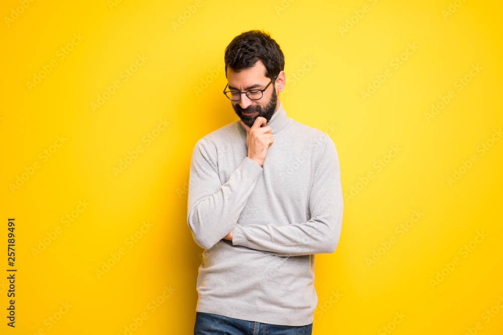 Wall mural man with beard and turtleneck looking down with the hand on the chin