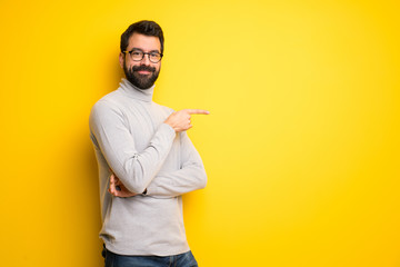 Man with beard and turtleneck pointing finger to the side in lateral position