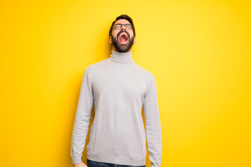 Obraz premium Man with beard and turtleneck shouting to the front with mouth wide open
