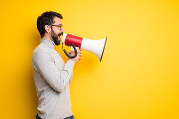Man with beard and turtleneck shouting through a megaphone to announce something in lateral position