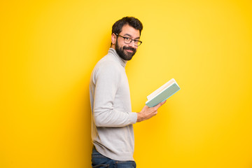 Man with beard and turtleneck holding a book and enjoying reading